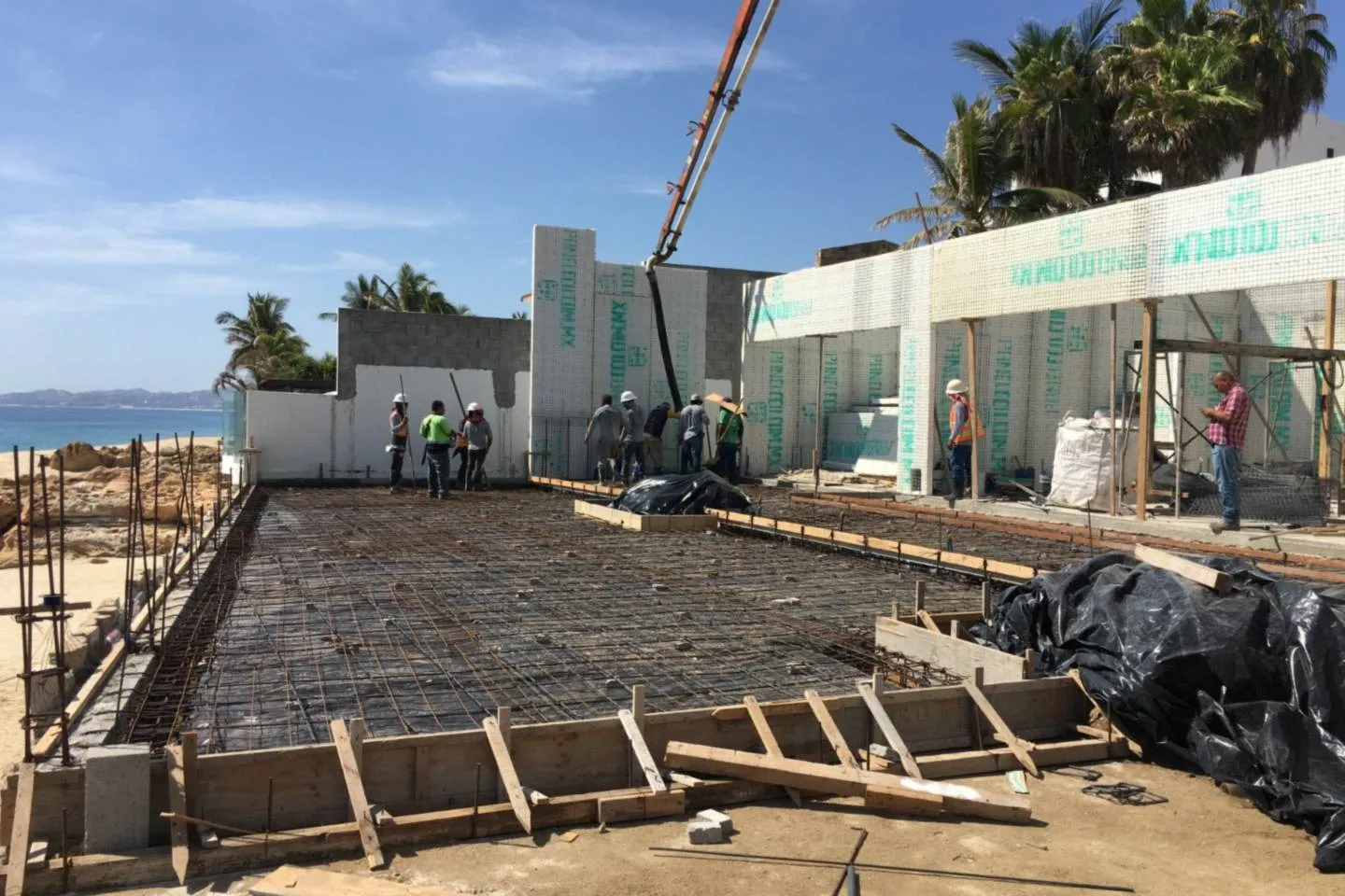 Foundation rebar and crew at work, ocean beyond, El Encanto project